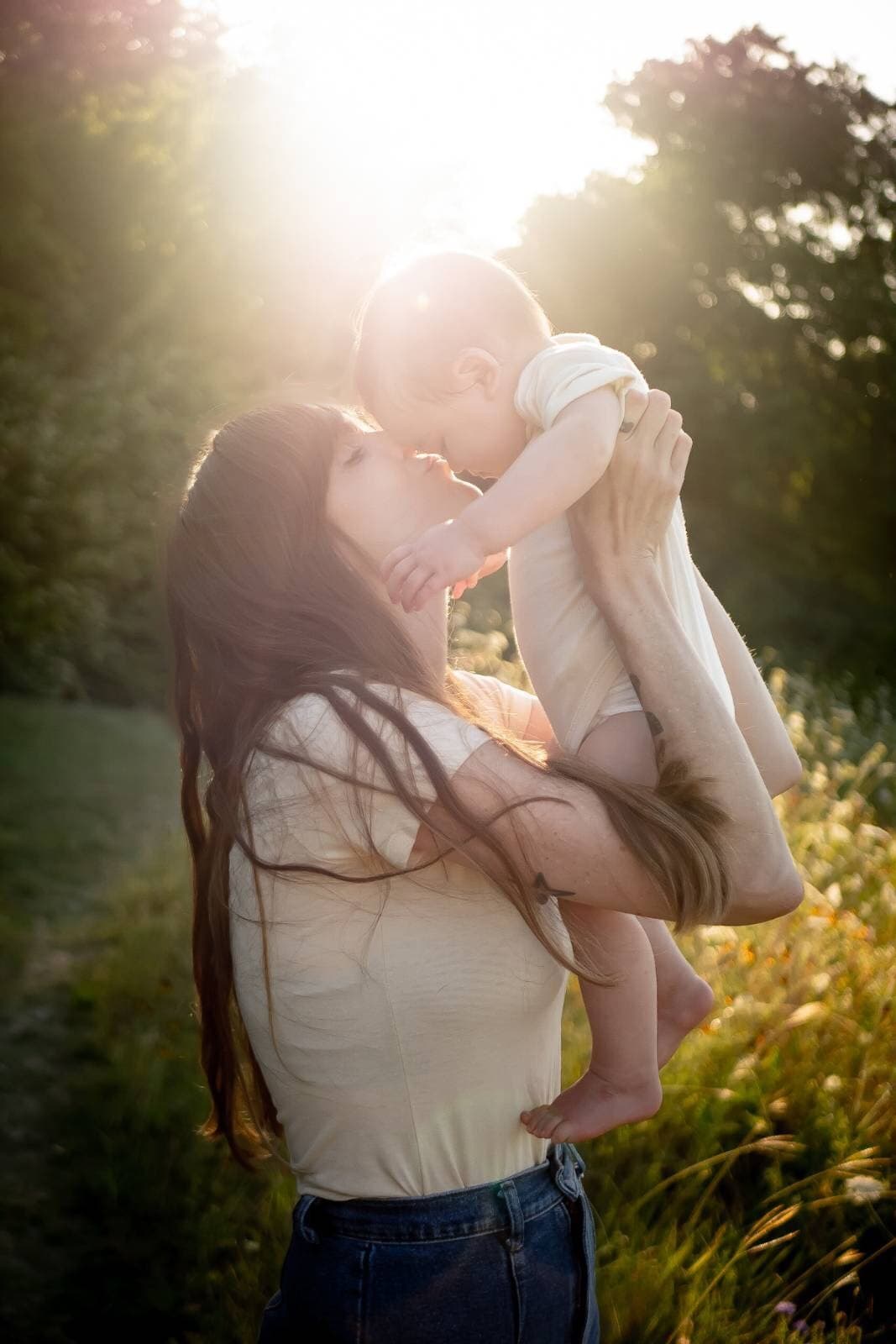 Megan lifting her daughter into the golden-hour sunlight