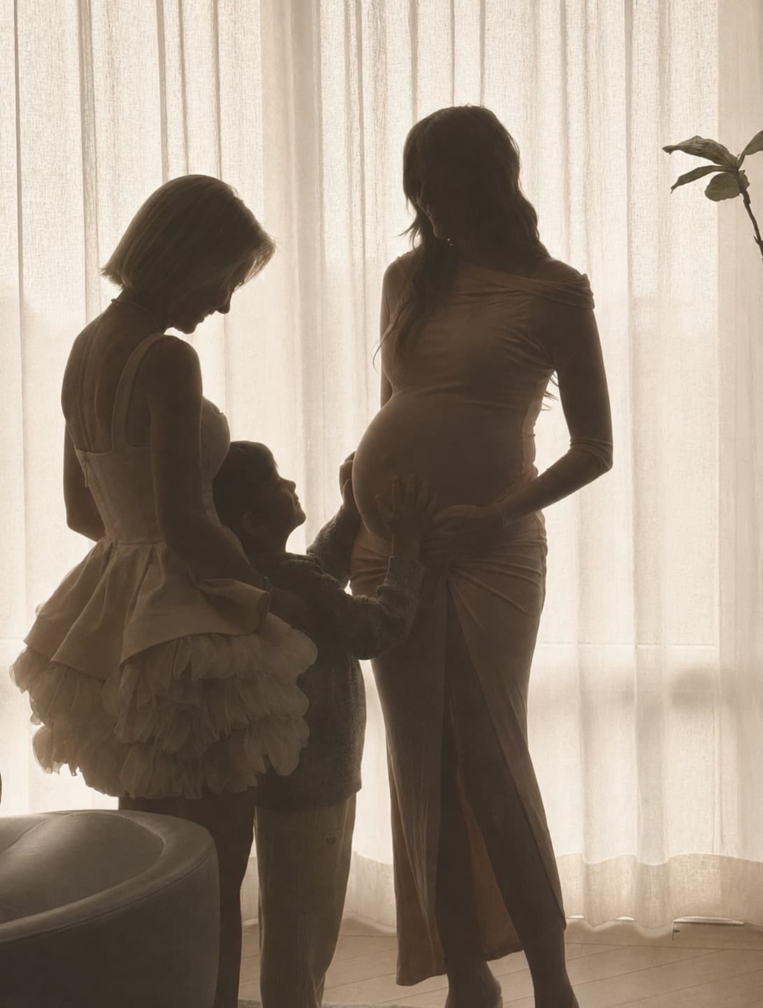 Megan, pregnant as a surrogate, with the intended mother and a child reaching toward the baby